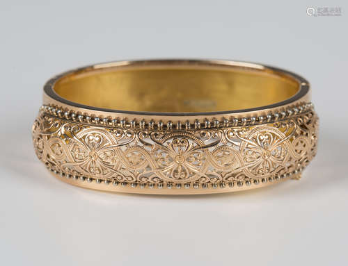 A rose gold oval hinged bangle, circa 1900, the front with p...