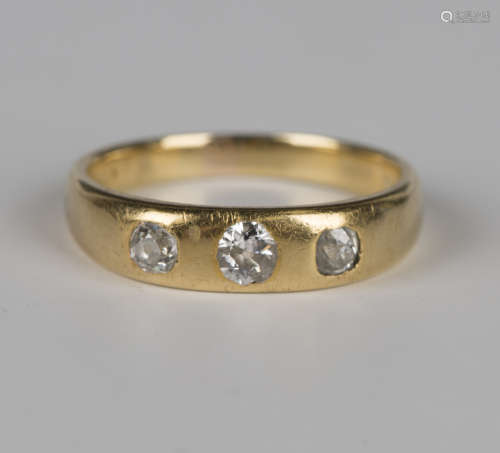 A gold and diamond three stone ring, gypsy set with a row of...