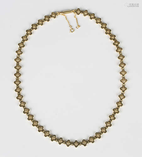 An 18ct gold necklace in a pierced quatrefoil shaped and bea...