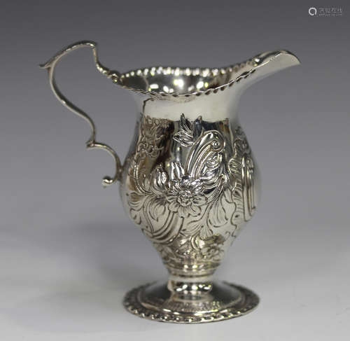 An Edwardian silver cream jug of ogee baluster form, embosse...