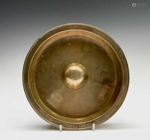 A Chinese polished bronze dish, the rim with character marks...