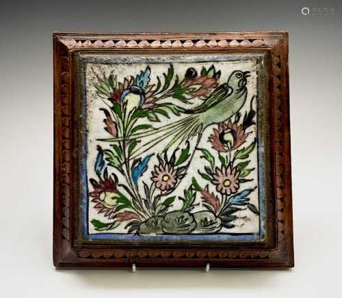 A Persian pottery tile, mounted in an oak stand, on turned f...
