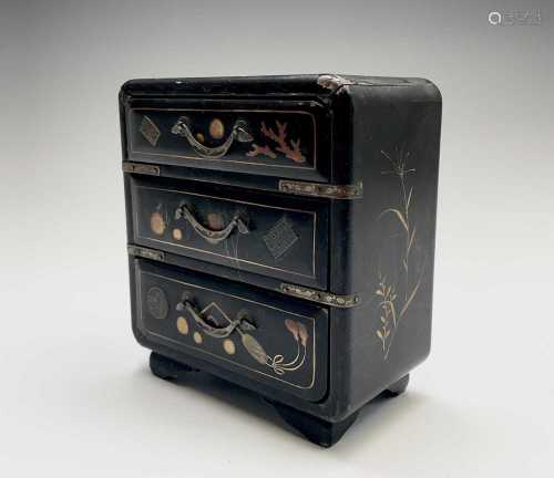 A Japanese miniature black laquer chest of drawers, early 20...
