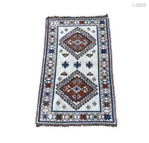 A Turkish rug, the ivory field with two polychrome lozenge m...