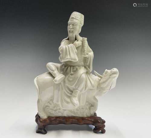 A Chinese blanc de chine figure of a sage seated upon a buff...
