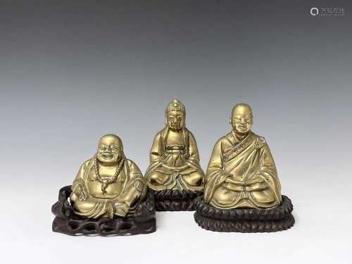 Three Chinese brass buddahs, early 20th century, on three go...