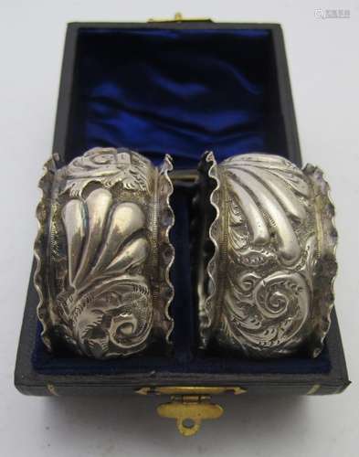 A pair of silver napkin rings heavily embossed with scrolls ...