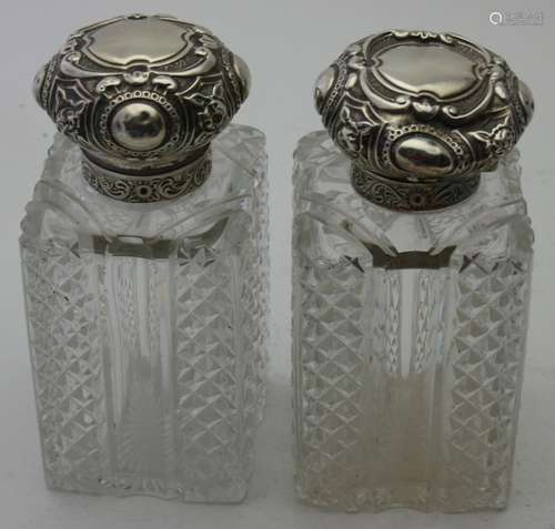 A pair of cut glass scent bottles with silver tops, London 1...