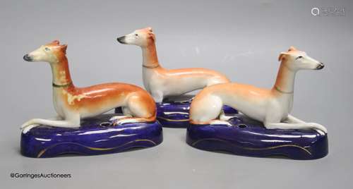 A pair of Staffordshire greyhounds and another similar, tall...