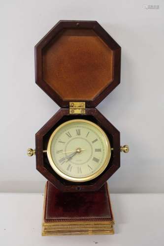 A clock housed in a wooden box with stand