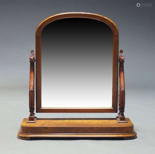 A Victorian walnut dressing mirror, of arched form, with car...