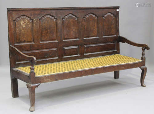 An 18th century oak settle, the panelled back above an uphol...