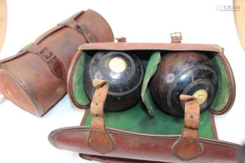 A pair of lignum vitae lawn bowls, in fitted leather travel ...