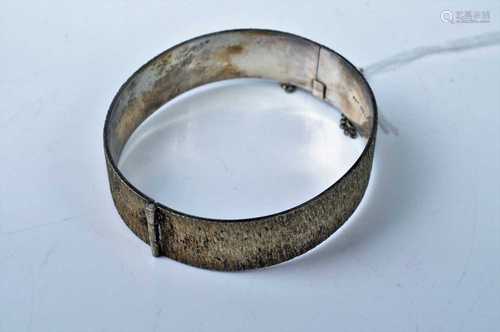 A brushed silver hinged, hallmarked bangle, with safety chai...