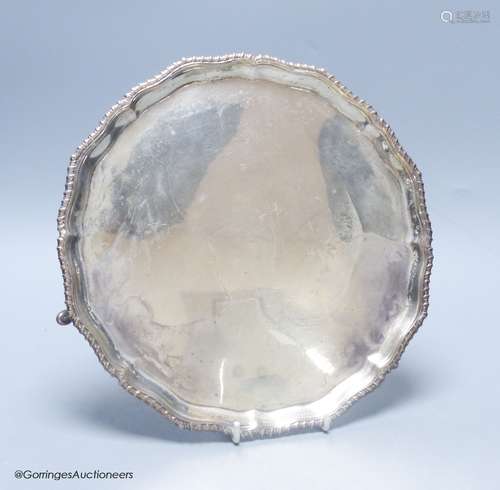 A circular silver salver with shaped gadrooned edge, on thre...