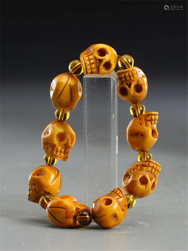 A STRING OF BONE CARVED SKULL-HEADS BRACELET