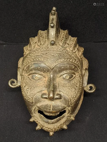 A Nigerian brass or bronze helmet mask, raised