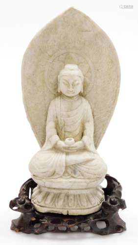 A Chinese carved limestone figure of Buddha seated on a lotu...