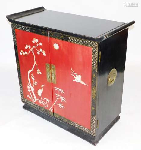 A Chinese black and red lacquered side cabinet, with two red...