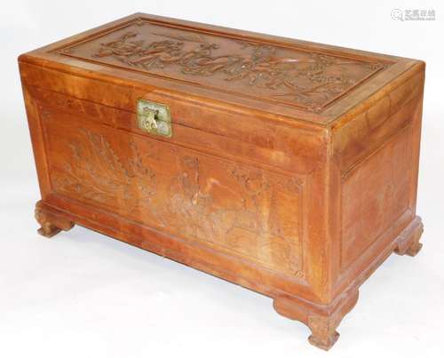 A Chinese camphorwood chest, the top carved in relief with a...