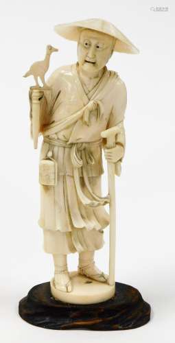 A Japanese carved ivory okimono of a falconer with staff, on...