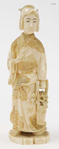 A Japanese ivory okimono of a woman with fan and bucket of c...