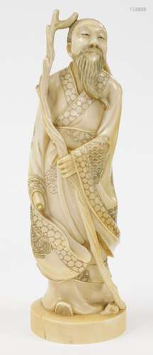 A Japanese ivory okimono of a man, in flowing robes with sta...