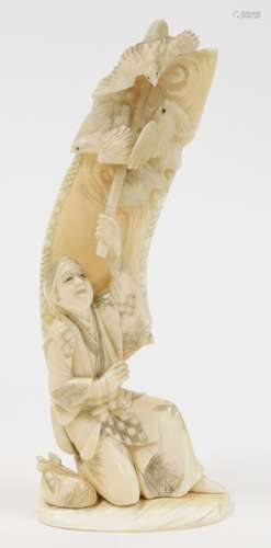 A Japanese ivory okimono of a kneeling man, holding aloft a ...