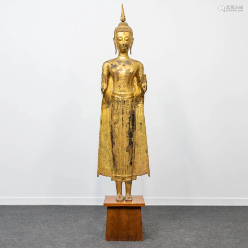 An antique buddha made of bronze and standing on a wood