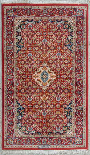 An Oriental hand-made carpet. Kerman with signature.