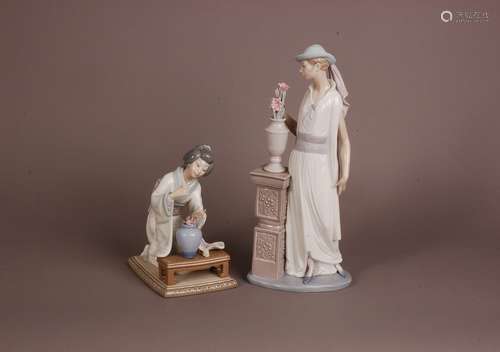 Two modern Lladro figures, one of an elegant lady stood with...