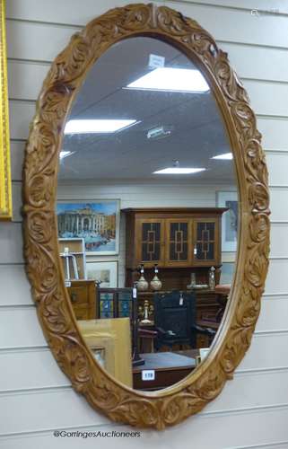 A carved oak oval framed wall mirror, width 70cm, height 109...