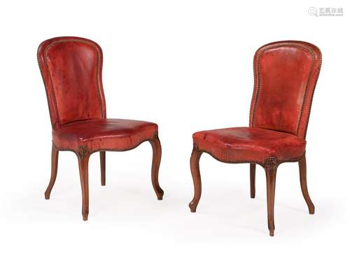 A SET OF EIGHTEEN WALNUT AND LEATHER UPHOLSTERED DINING CHAI...