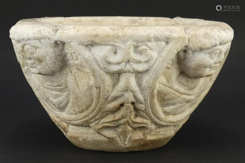 Antique white marble baptism font carved with faces,