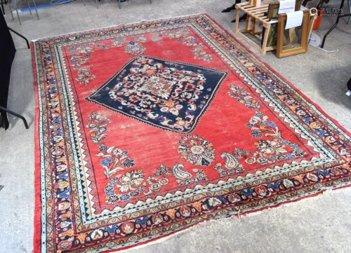 A large Middle Eastern red ground carpet decorated with