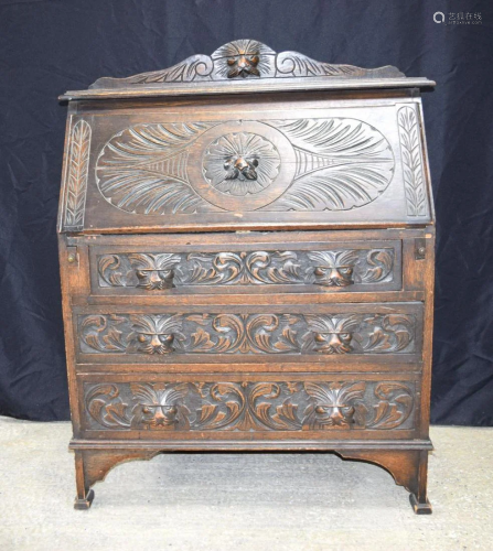 An Arts & Crafts three drawer carved Oak writing