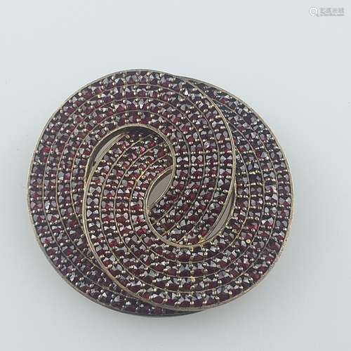 Broche en grenat - tombac, forme de boucle ajourée, sertie d...