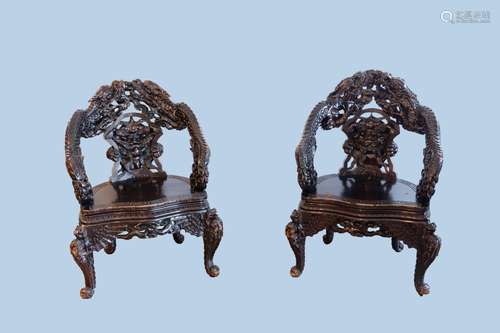 A pair of Chinese or Japanese carved wooden 'dragon' chairs,...