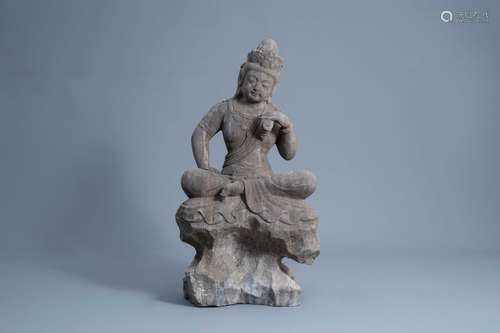 A Chinese carved stone figure of Buddha seated on a rock, Qi...