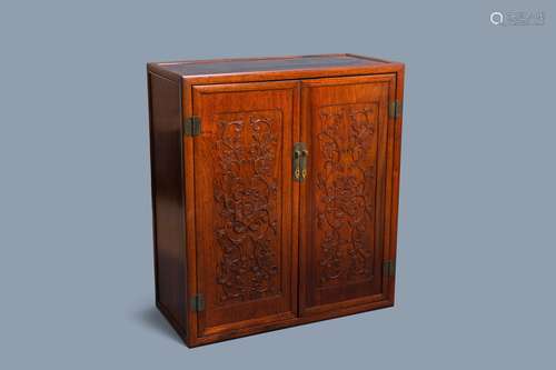 A Chinese wooden two-door cupboard with carved floral panels...