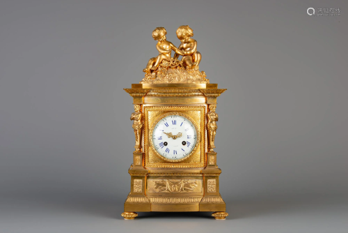 A gilt bronze mantel clock crowned with two putti and a