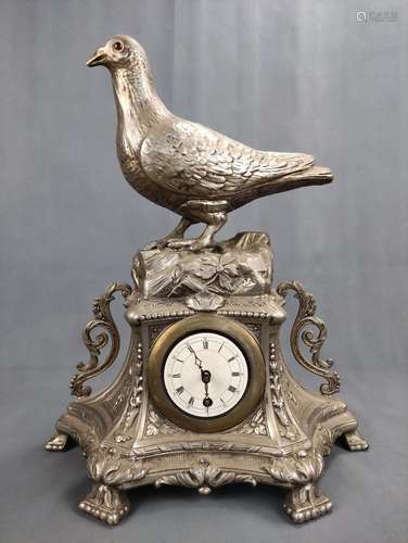 A table clock with a fully plastic dove, on a floral decorat...