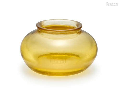 A small transparent pale-amber-yellow glass jar