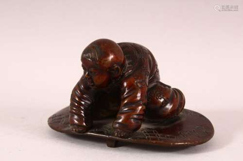 A CHINESE BRONZE FIGURE OF A BOY PLAYING - the boy knelt upo...