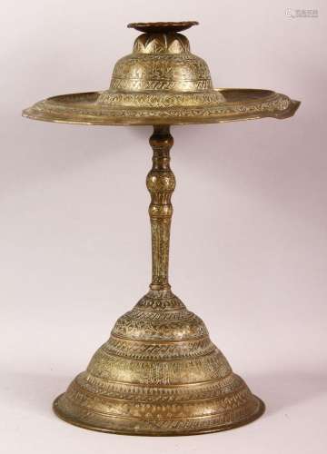AN ISLAMIC BRASS CANDLESTICK, engraved with bands of calligr...