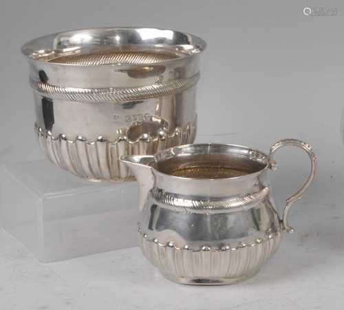 A late Victorian silver cream jug and sugar bowl duo, each o...