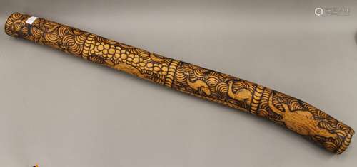 A carved wooden didgeridoo. 109 cm long.