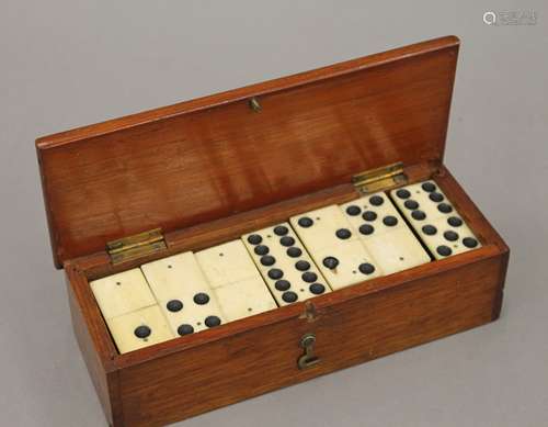 A boxed set of bone and ebony dominoes. The box 19.5 cm wide...