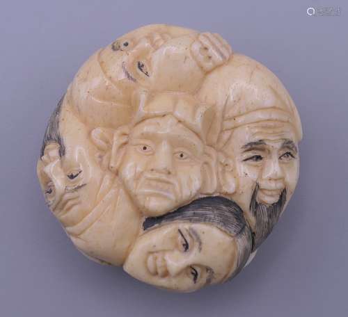 A bone netsuke formed as faces. 4 cm diameter.