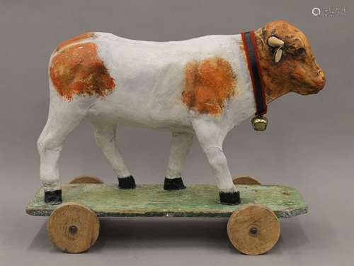 A vintage papier mache cow on wheeled stand. 33 cm long.